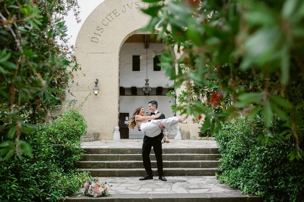 Groom lifting bride under the archway during Santa Barbara Courthouse wedding photos.