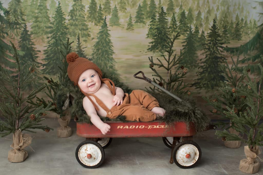 Christmas newborn photography of baby with personalized “First Christmas” ornament