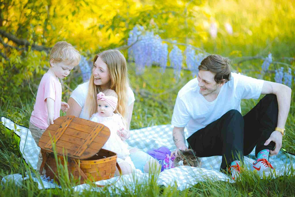 Family enjoying a summer picnic in coordinated outfits for family photos, featuring light pastel colors and relaxed summer fashion.