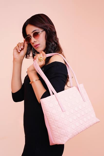 Fashion lifestyle product photography of a woman in a black dress holding a designer purse, highlighting.
