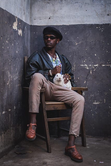 Man sitting on a chair gently holding a cat in his hands indoors