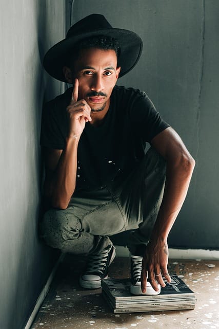 Man wearing a hat sitting on the floor indoors in a relaxed pose