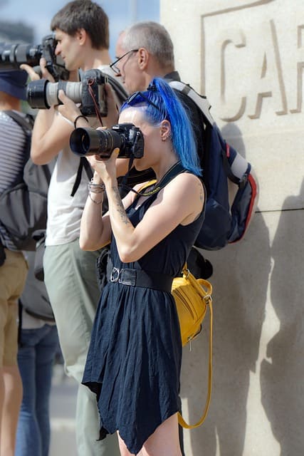 Group of people using DSLR cameras for photo booths photography, capturing photos with their own cameras while adjusting settings, not smiling, focused on taking shots