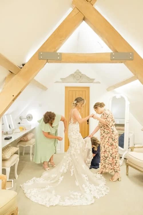 wedding photos bride getting ready with the bridal party helping the bride adjust her gown.