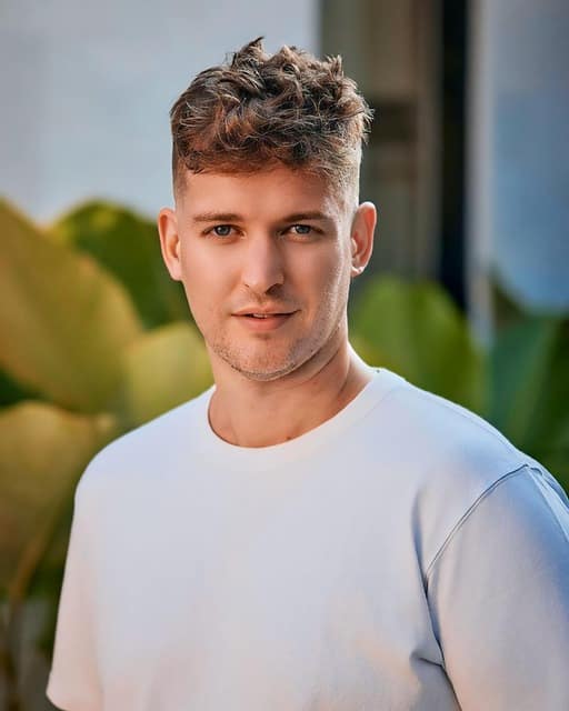Man wearing a crisp white shirt standing confidently against a neutral background