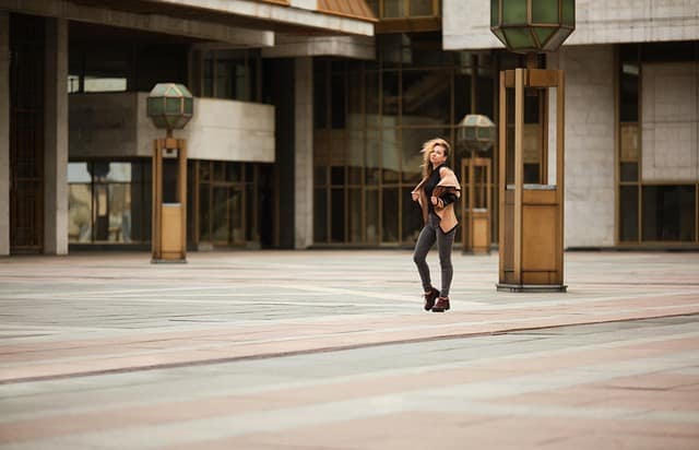 A fashionable girl in black clothes standing on the street with a confident pose.