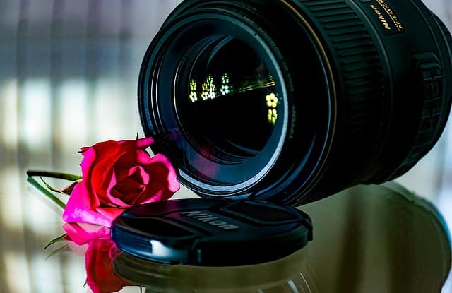 Wedding photography lens with a flower placed beside it, symbolizing creativity and elegance in wedding photography.