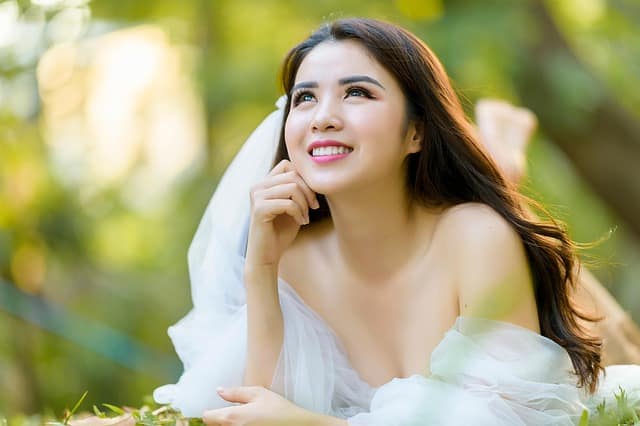 Close-up headshot of a woman smiling with radiant glowing skin and soft background
