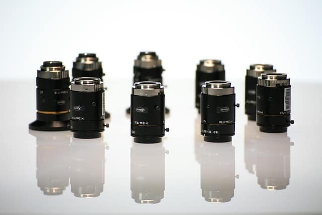 Professional wedding photography lenses arranged on a wooden table for wedding photographers.