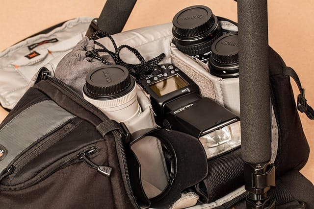 Flat lay of top travel photography accessories including camera, lenses, tripod, and memory cards neatly packed for a photography trip.