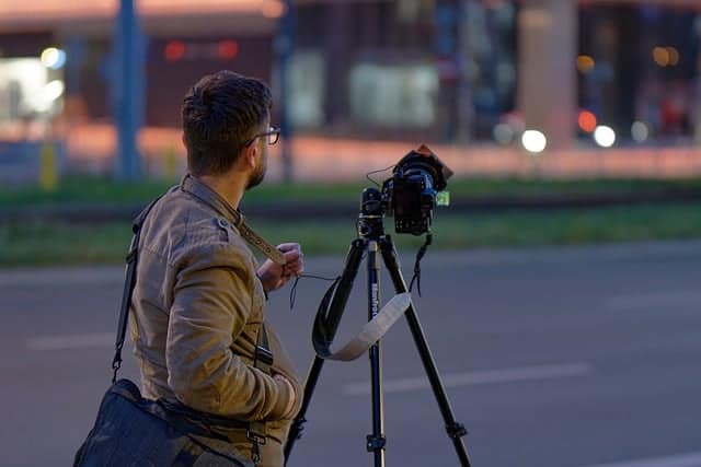 Wedding photographer on road with stabilizer and camera bag capturing photos outdoors
