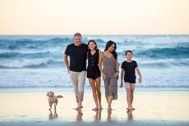 A happy family walking barefoot on the sand during golden hour for beach family photos