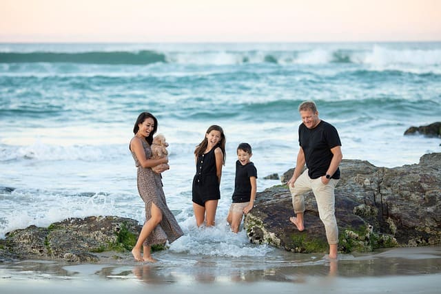 Close-up of a smiling family during sunset with warm golden light on the beach.