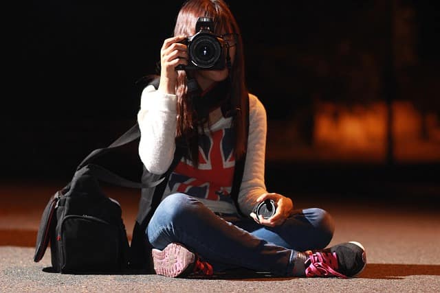 Girl holding a good cameras for night photos while capturing city lights at night