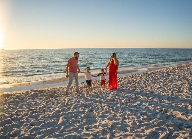 Family walking along the shoreline during golden hour for beautiful Sunset Beach Family Photos.