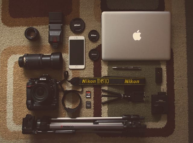 Overhead shot of complete travel photography gear setup including camera, tripod, lenses, laptop, and other essential accessories for travel photographers.