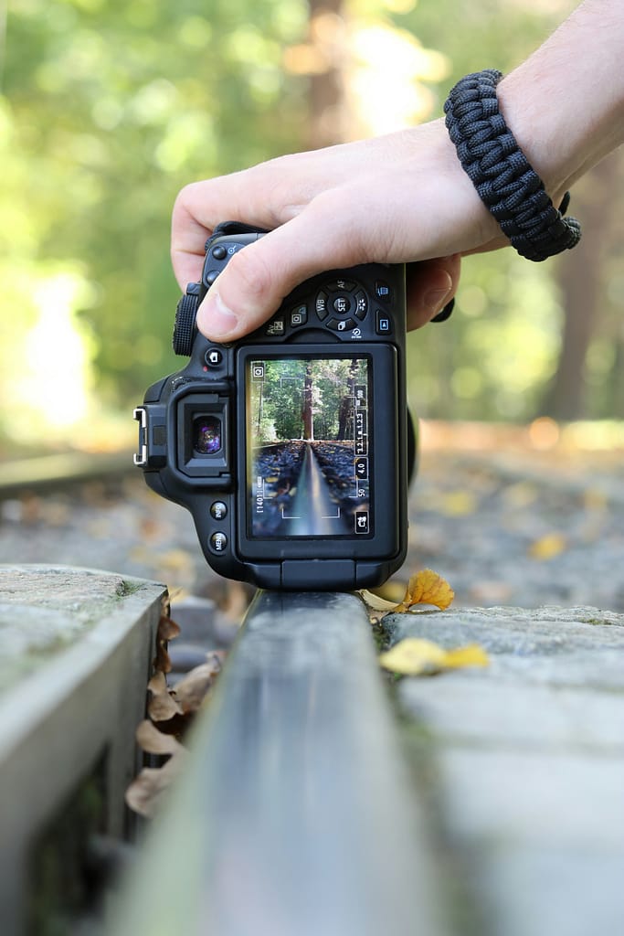 Close-up of a DSLR camera for photo booth photography, showing the camera screen focused on outdoor scenery with a person adjusting the shot