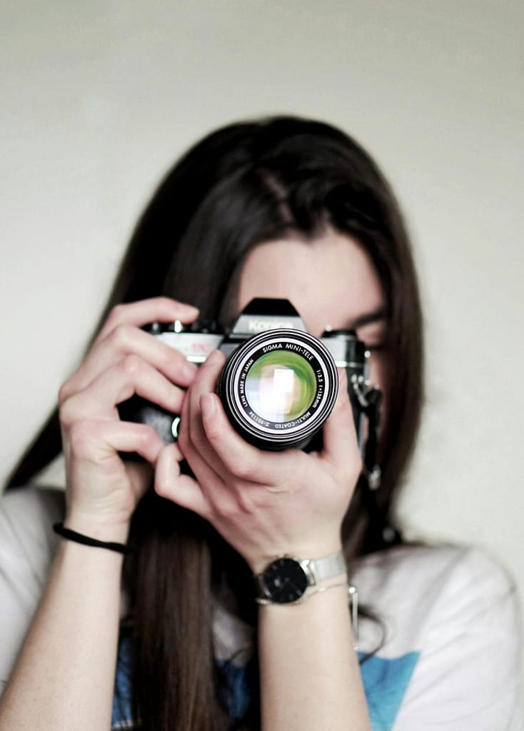 Girl taking a photo with a camera during outdoor photography session